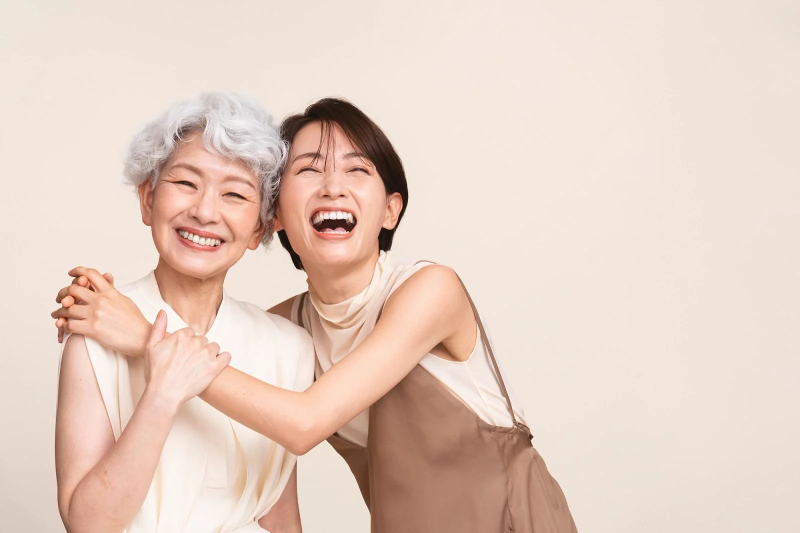 Two happy women, one older and one younger, embracing and laughing.