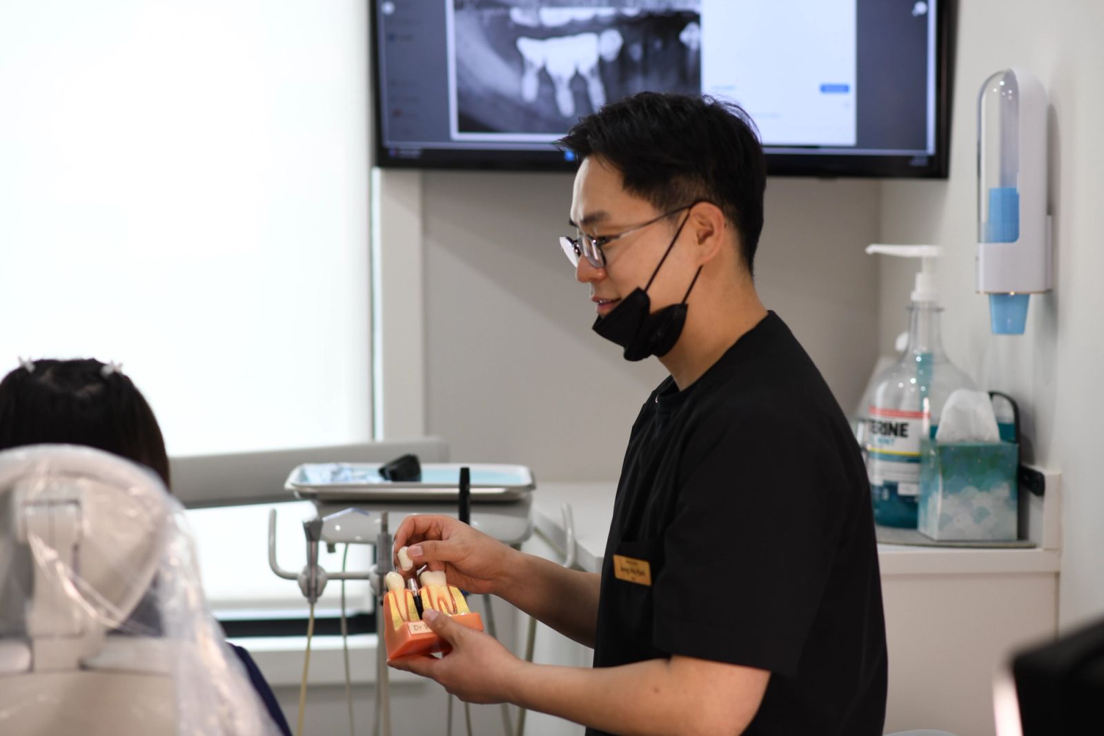 a dentist is holding a model of a tooth in a dental office .