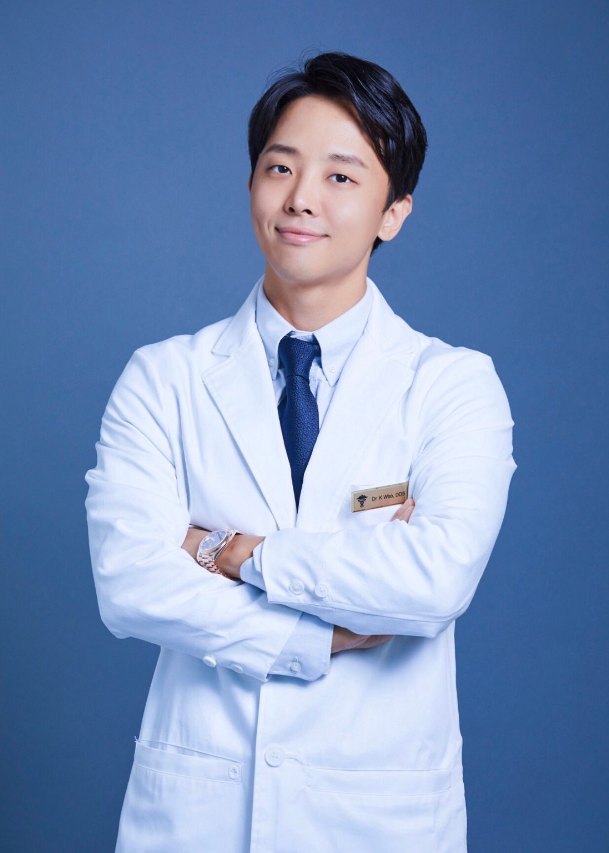 a man in a white coat and tie has a name tag that says dr. s. kim