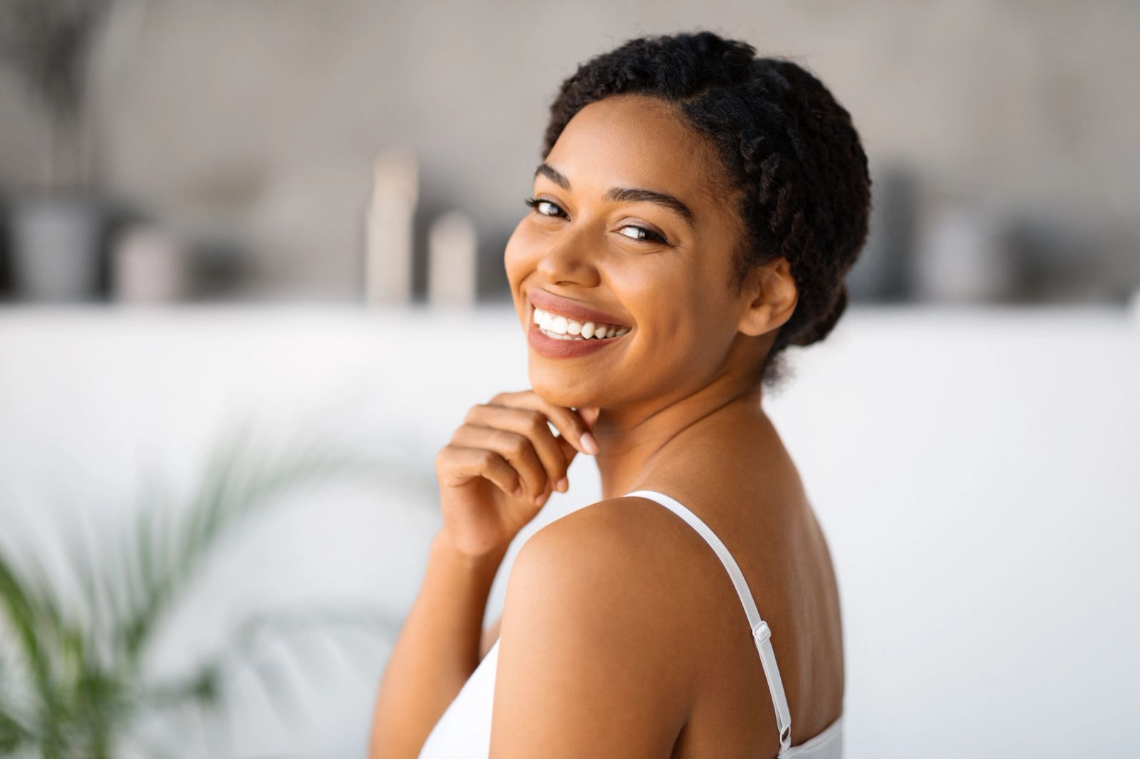 Smiling woman with braided hair looks over her shoulder.