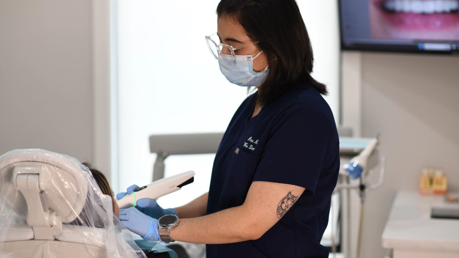 a woman is sitting in a dental chair while a dentist examines her teeth .