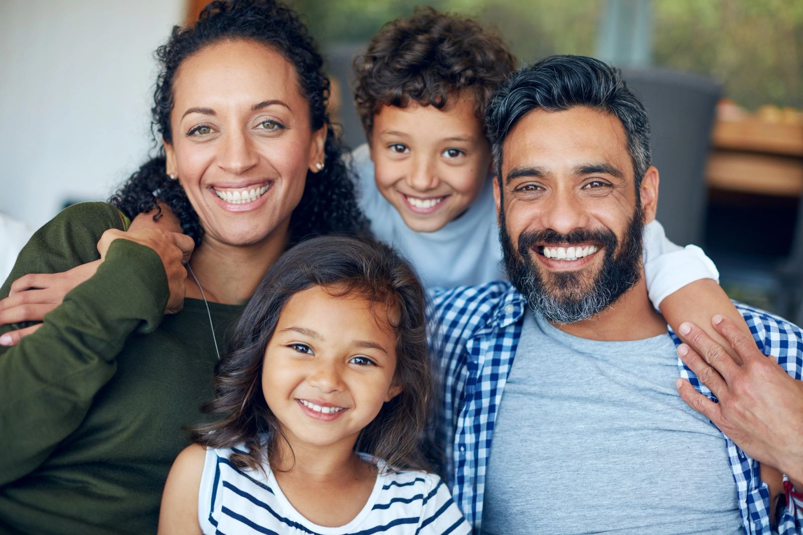 A happy family of four, including two adults and two children, smiling at the camera.