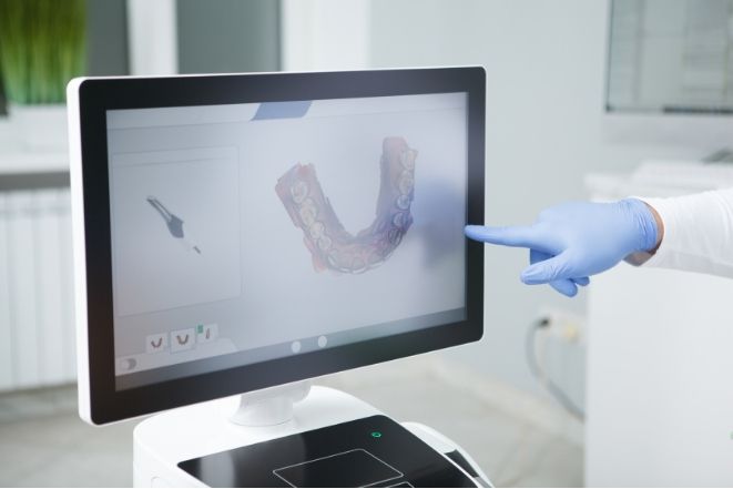 a person is pointing at a computer screen with a picture of a mouth on it .